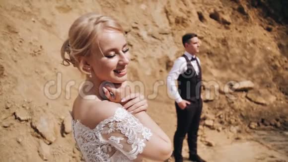 女孩站在她的年轻人旁边背景是沙堆她从镜头看向她的男朋友视频的预览图