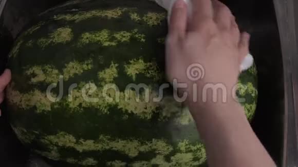 女用手在厨房水槽里用白布擦拭大绿西瓜视频的预览图