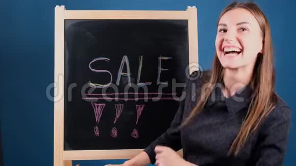 铭售写在黑板上一个快乐的女孩正在附近跳舞等待折扣视频的预览图