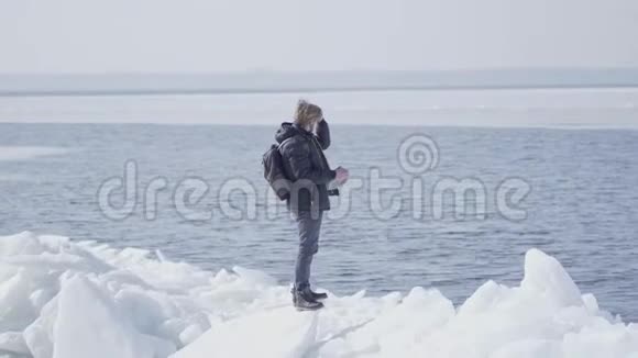 那人穿着一件温暖的外套站在冰川上挺直了头发看着远处神奇的自然雪视频的预览图