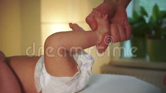 熟练的治疗师在白色沙发特写上擦小男孩的腿视频的预览图