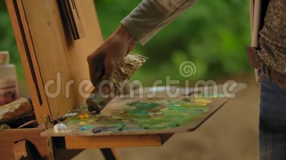 女艺术家挤压一个管与黄色橙色油漆在调色板上视频的预览图