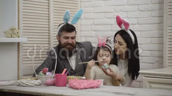幸福的家庭正在为复活节做准备可爱的小女孩戴着兔子耳朵妈妈爸爸和他们的女孩视频的预览图