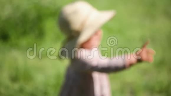 小女孩站在草地上戴着草帽和连衣裙肚子很滑稽天气很热视频的预览图