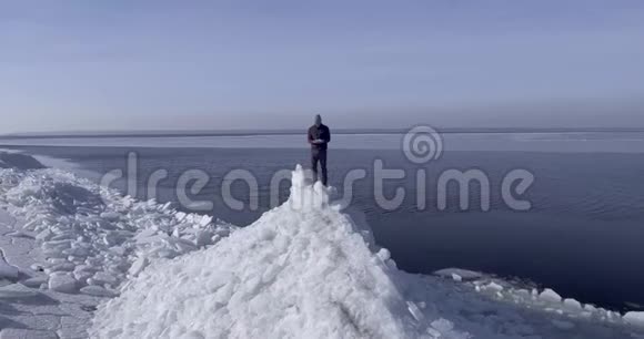鸟瞰年轻活跃的快乐男子停留在冰冰冰川附近的冬季海洋海岸线医生飞进了视频的预览图