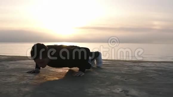 年轻运动员在户外做俯卧撑早上在大海或海洋前的木制泡沫健身和视频的预览图