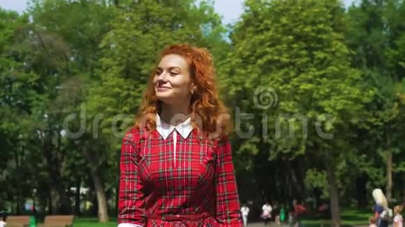 阳光明媚的一天幸福的红头发女孩在绿色公园散步视频的预览图