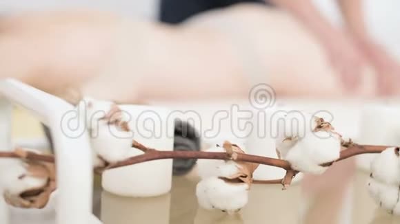 在一位男性物理治疗师的背景下用一束棉花在按摩桌上特写蜡烛视频的预览图