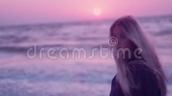 女孩模特看着镜头侧面黎明大海海浪地平线背景上的风视频的预览图