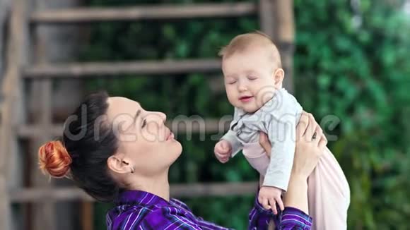 中度特写快乐的母亲抱着她的小宝宝微笑吹着风享受母亲的生活视频的预览图