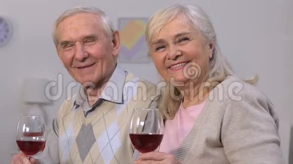 可爱的老夫妇带着酒杯看着相机微笑着庆祝视频的预览图
