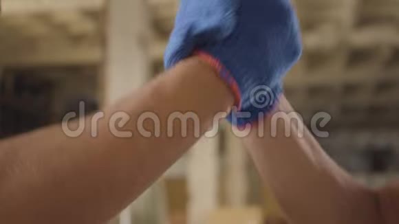 两名戴蓝色工作手套的男性白种人工人的高握手特写强壮肌肉的建筑工人视频的预览图