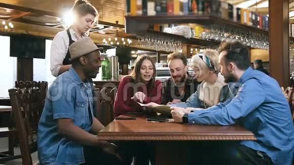 一群年轻英俊的朋友从菜单到酒吧酒吧里微笑的女服务员都在点菜视频的预览图