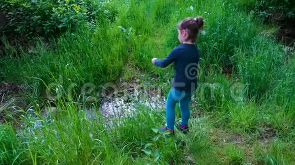 小女孩在大自然中玩着一把刀在树林里把草切成一条小溪还有一把求生的刀工具视频的预览图