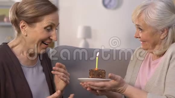 老年妇女向朋友赠送生日蛋糕女士许愿吹蜡烛视频的预览图