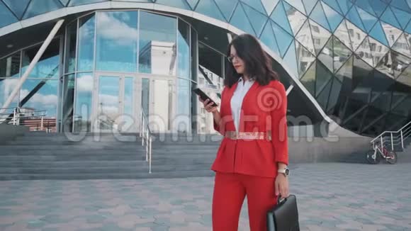 自信的商务女性穿着正式西装在户外使用手机视频的预览图