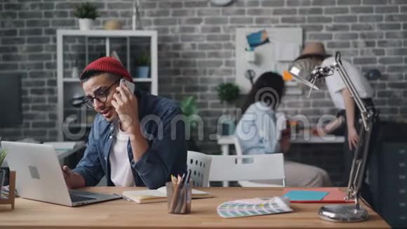 企业主用智能手机在创意办公室的办公桌前打电话视频的预览图