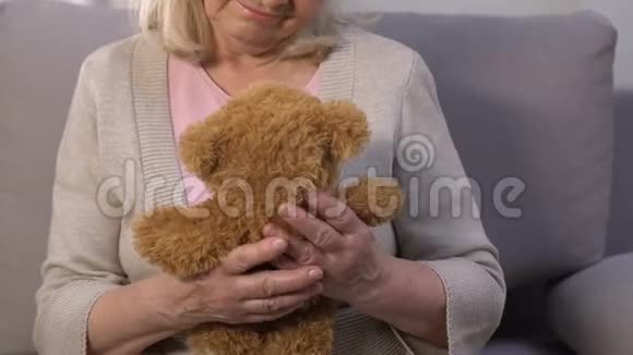 孤独的老母亲拥抱泰迪熊回忆忙碌的孩子回忆视频的预览图