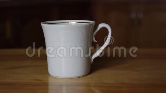 棕色木柱桌上的白瓷咖啡杯视频的预览图