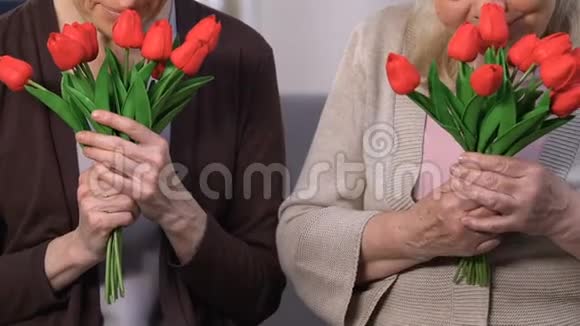 快乐的老年女性闻着美丽的花朵母亲节送礼物视频的预览图