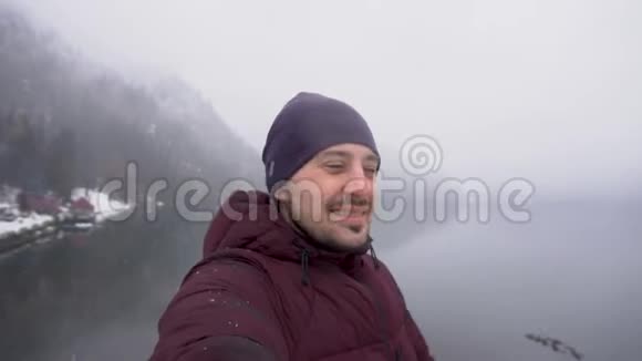 旅行概念男子自拍并显示里萨湖在阿布哈兹冬季视频的预览图