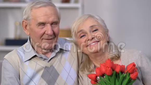 微笑的老年夫妇拥抱女人闻花香庆祝结婚纪念日视频的预览图