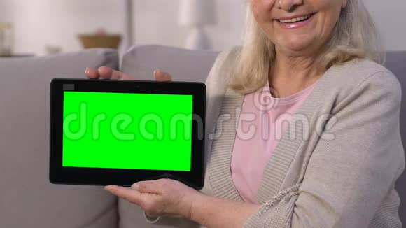 微笑的老太太用绿色屏幕显示平板电脑快速上网视频的预览图