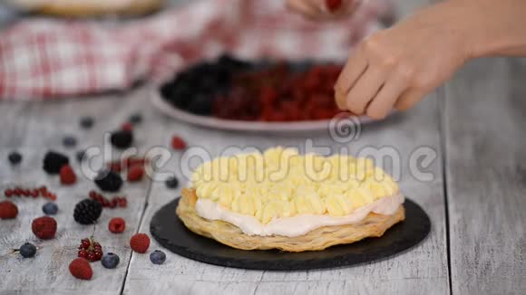 糖果女孩把夏天的浆果放在奶油层蛋糕上女人准备一个奶油和浆果蛋糕视频的预览图