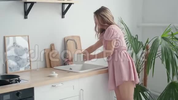 可爱的快乐女孩在清晨把水倒进厨房的水壶里视频的预览图