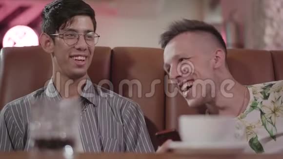 两个男朋友在餐厅休息的肖像坐在皮革沙发上谈笑风生他用的是视频的预览图