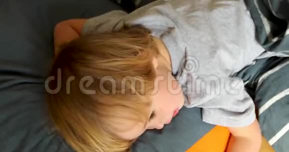 累了的孩子躺在床上看着视频的预览图