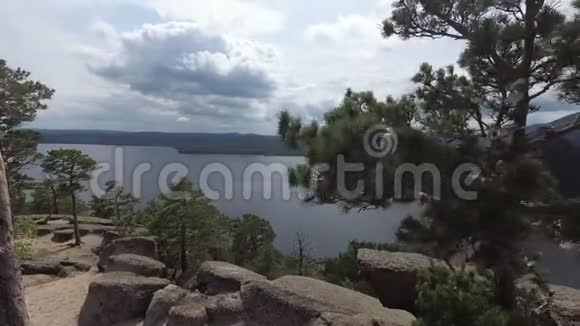 从山上俯瞰岩石湖树枝上挂着岩石和树木的愿望丝带视频的预览图