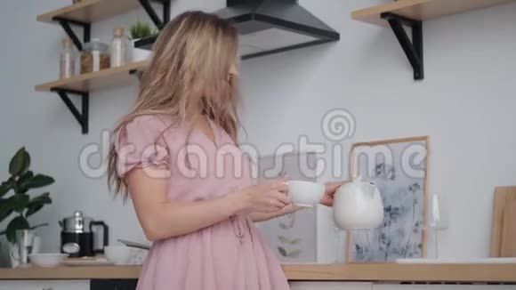 可爱的女孩带着迷人的微笑从茶壶里倒茶视频的预览图