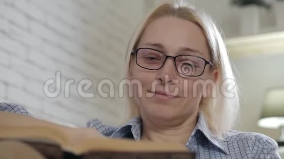 可爱的女人热情地看书享受爱好在沙发上放松视频的预览图