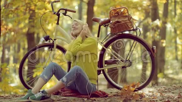 秋天和树叶飘落的梦想耳机概念无忧无虑的女人户外大气时尚照片年轻美丽视频的预览图