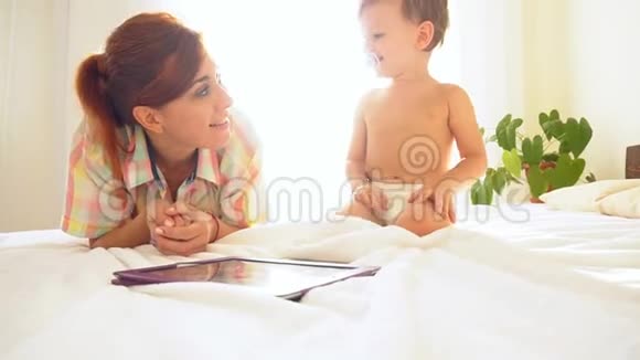 妈妈和小男孩早上在床上看平板电脑视频的预览图
