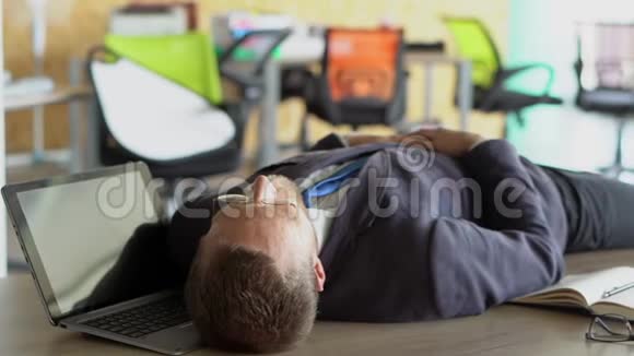 疲惫的时尚工人睡在办公室的桌子上视频的预览图