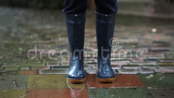 穿着深蓝色雨靴的人在后院城市街道或公园铺好的道路上行进视频的预览图