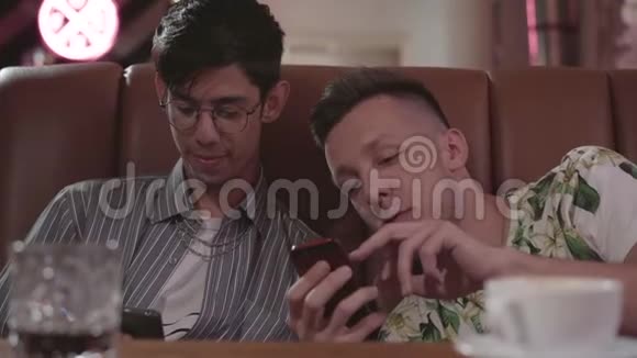 两个男性朋友坐在皮革沙发上休息的肖像把他朋友的照片放在视频的预览图