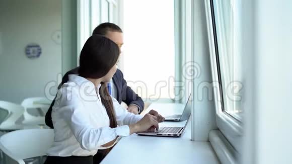 美丽的女孩和她的同事坐在桌边一起工作视频的预览图