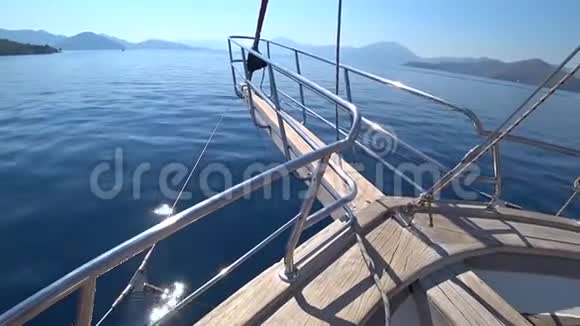 在晴朗的晴天游艇迅速驶过蔚蓝的大海驶向小岛屿游艇的船头特写视频的预览图