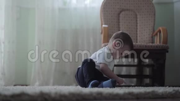 可爱的小男孩坐在地板上毛茸茸的地毯上独自玩耍女人脱下漂亮的粉红色高跟鞋坐着视频的预览图