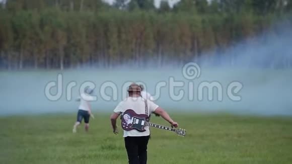 摇滚乐队的音乐家跑到烟雾弥漫的一大片田野他们只是玩玩而已好心情视频的预览图