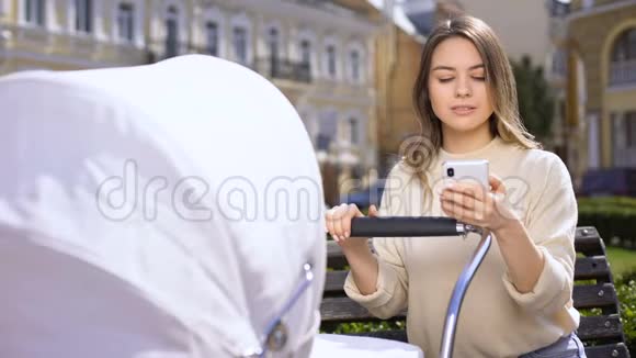 不负责任的女性在智能手机上聊天忽视婴儿车里哭泣的婴儿视频的预览图