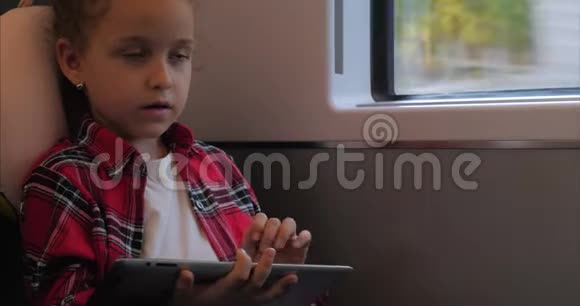 可爱的小女孩用平板娱乐儿童休闲时间乘坐电动火车玩手机游戏视频的预览图