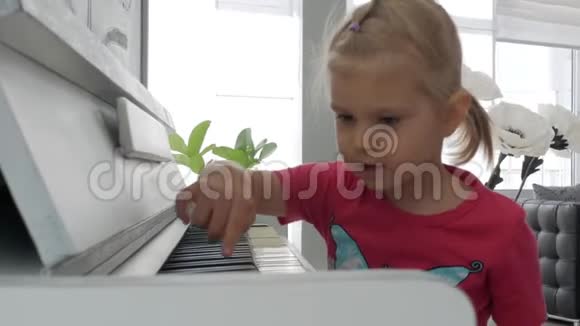 一个坐在白钢琴旁的小女孩按下键视频的预览图