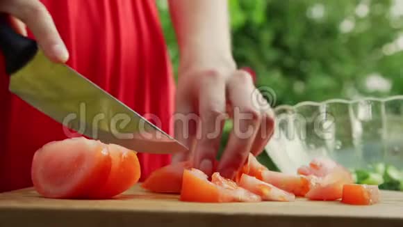 熟练的女士在棕色木板上切熟的番茄片视频的预览图