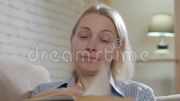 可爱的女人热情地看书享受爱好在沙发上放松视频的预览图