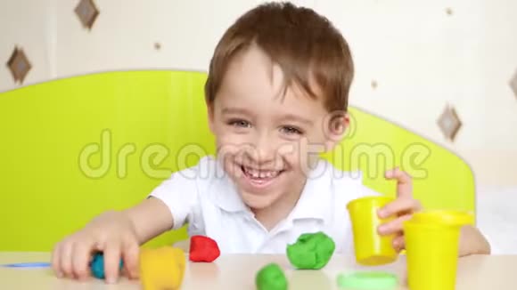 一个快乐的孩子在桌子上玩着五颜六色的塑料或面团图形作为游戏视频的预览图