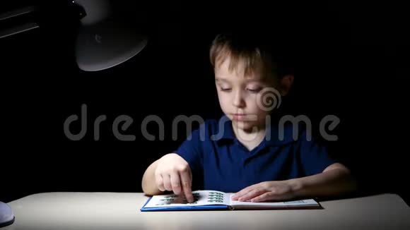 一个孩子用手指指着书中的图画在家里睡觉前他坐在一张桌子旁桌子被一个视频的预览图